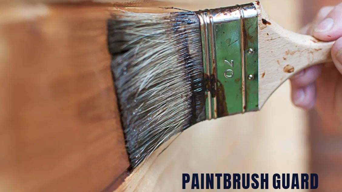 Paintbrush with a paintbrush guard being used on wood.